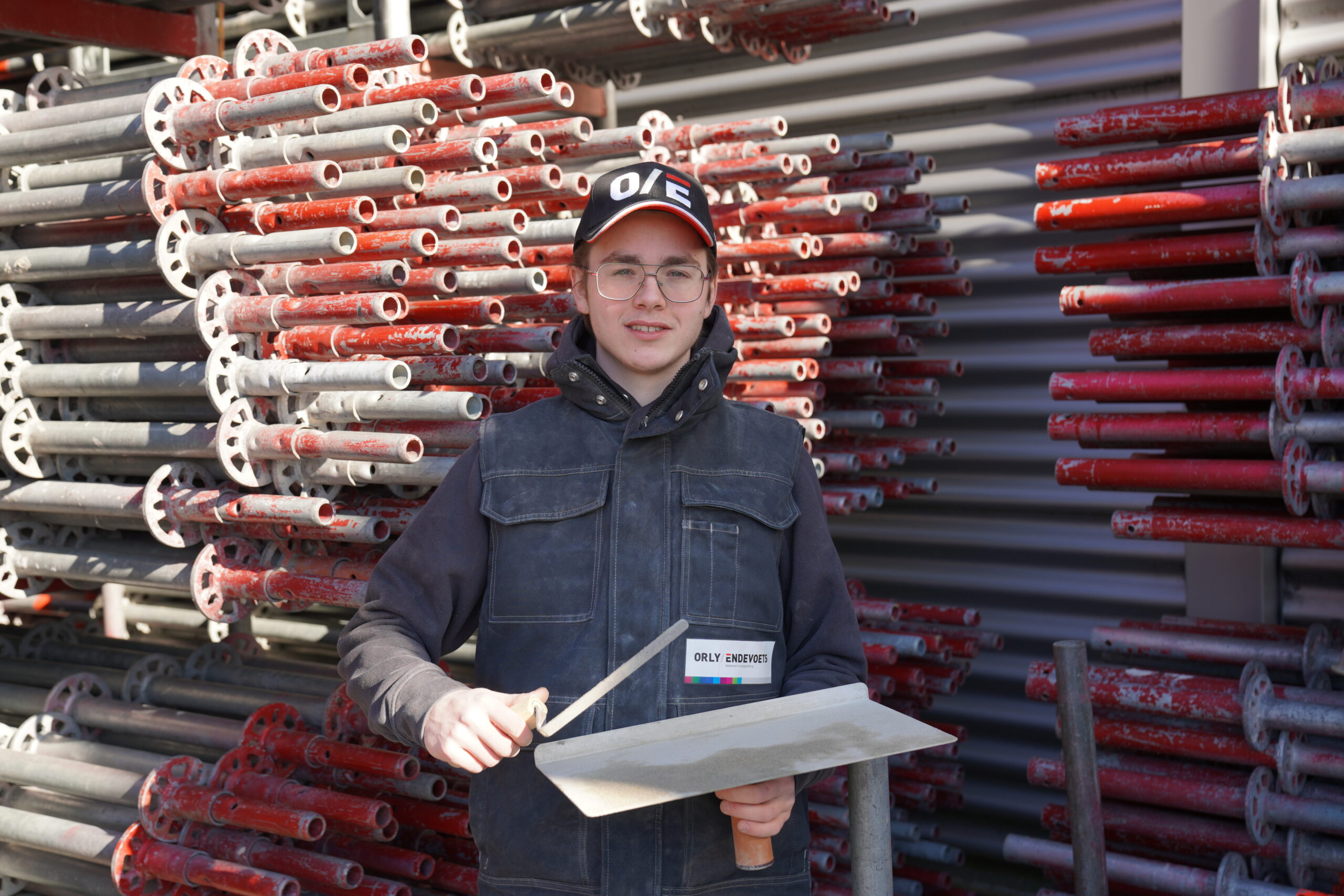 Bewoner wordt collega Bewoner draagt als bouwvakker zwarte werkkleding en houdt een voegspijker en voegbord vast. Bewoner wordt collega.