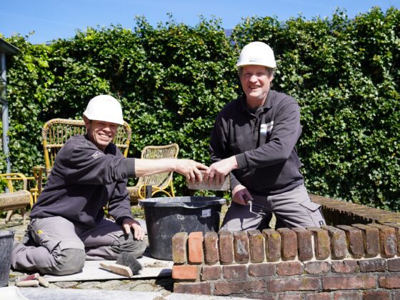 Twee bouwvakkers bouwplaatsmedewerkers die samen een muur aan het metselen en voegen zijn