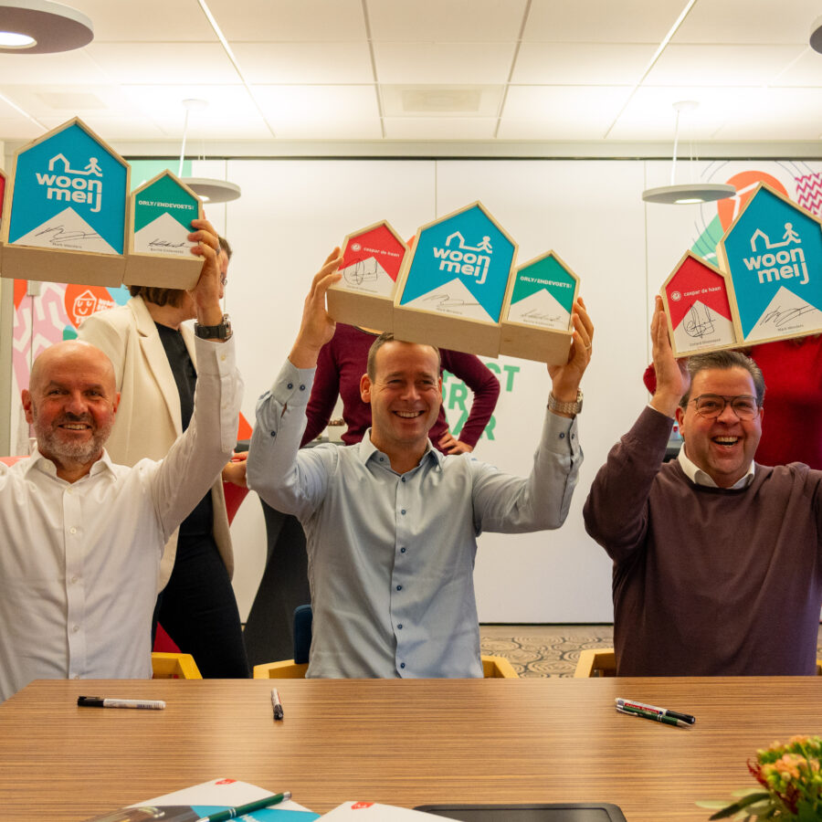 Berrie Endevoets van Orly & Endevoets, Mark Wonders van Woonmeij en Gerard Dinnessen van Caspar de Haan houden houten huisjes omhoog met daarop hen handtekening. Dit symboliseert de ondertekening van het handboek verduurzaming.